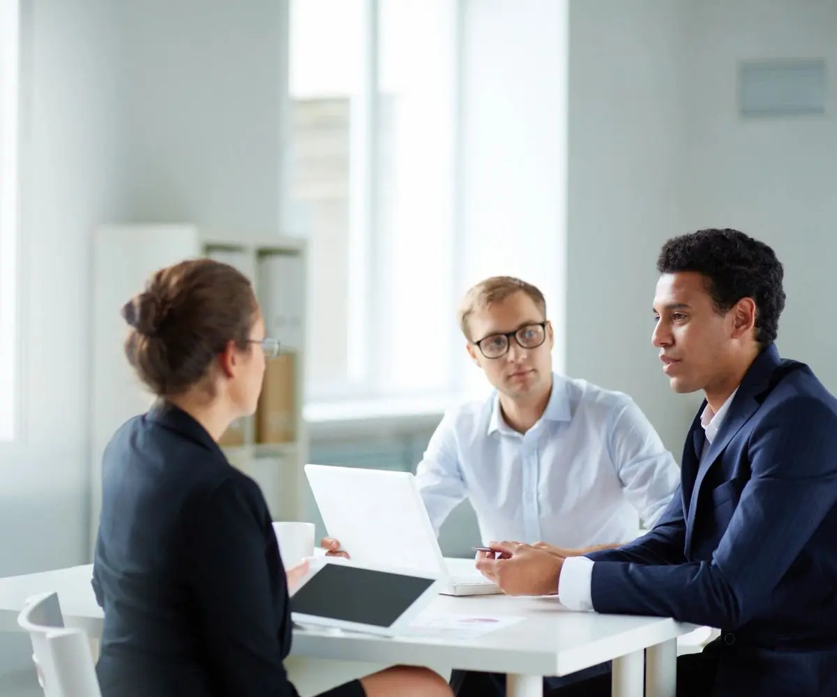 Three people sitting at a table talking to each other.