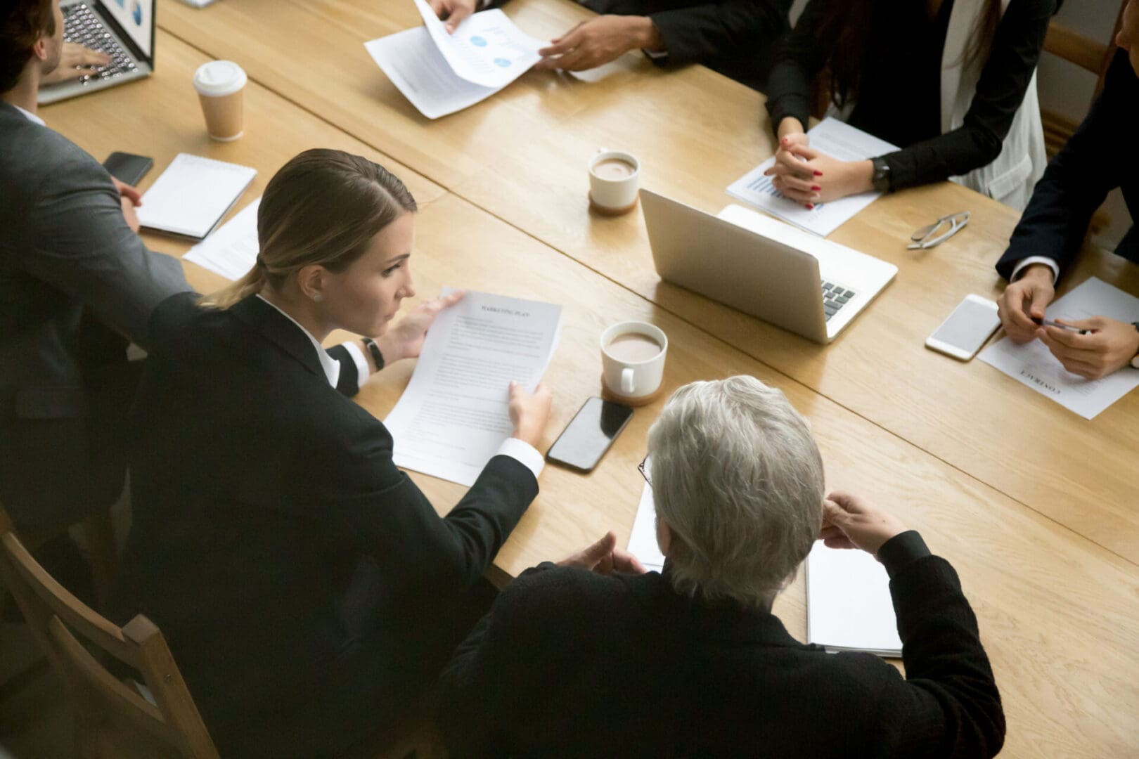 A group of people sitting at a table with papers and laptops.